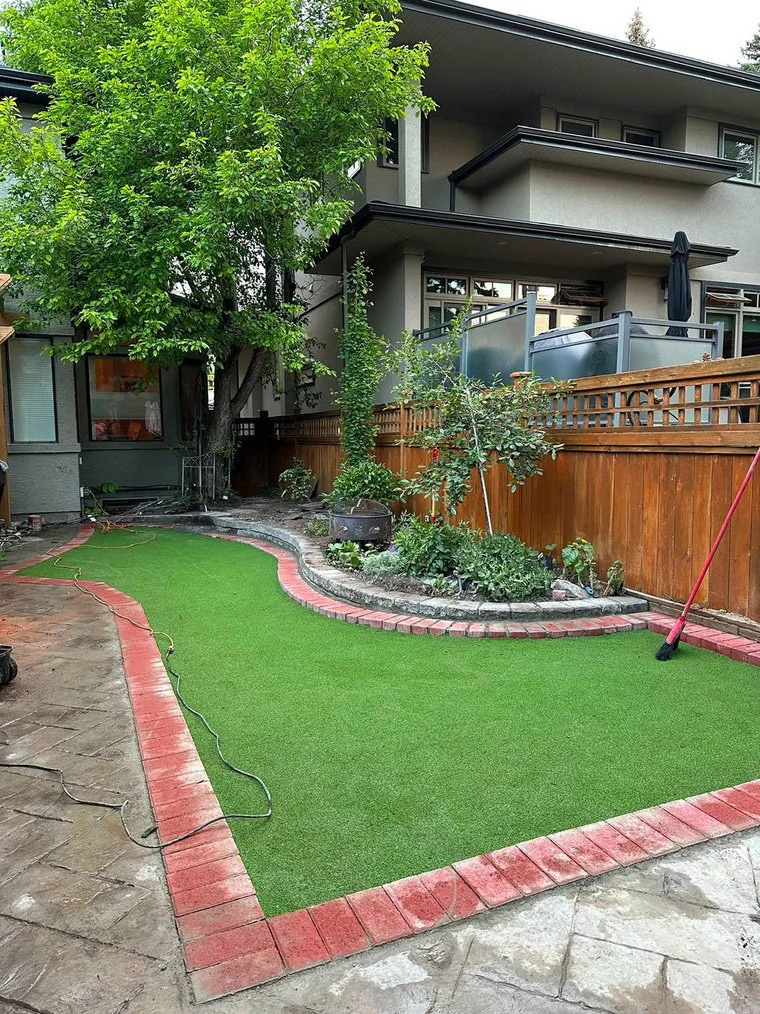 Backyard putting green with red-brick border and planted bed
