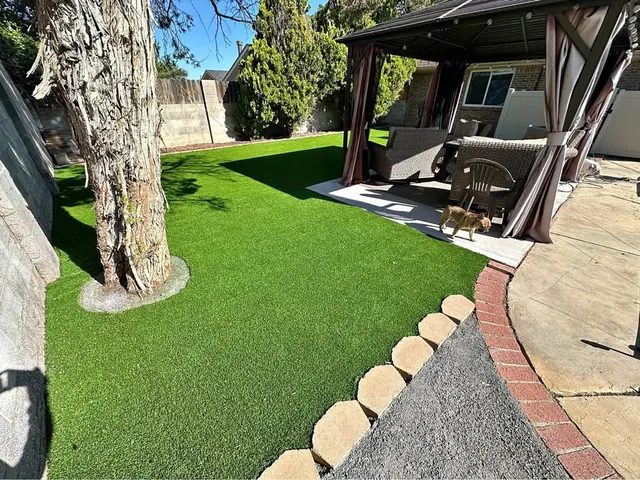 Artificial turf lawn wrapping a mature tree beside a covered patio