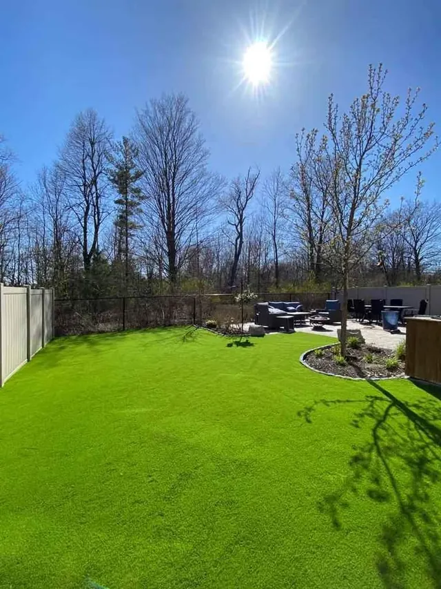 Large artificial turf backyard with a planted bed and seating area