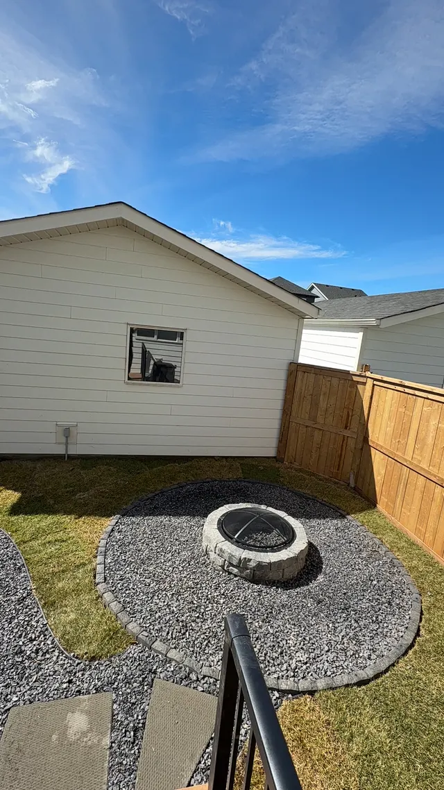 Fire pit set in rock with a slab path and turf