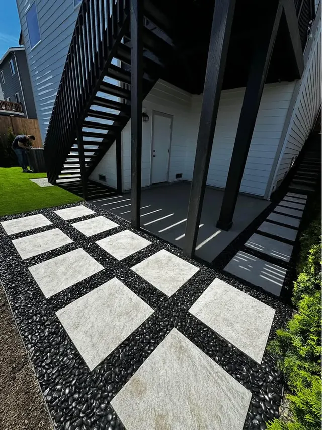 Slab stepping stones set in black rock beneath a staircase