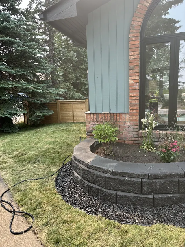 Curved block retaining wall enclosing a planted bed