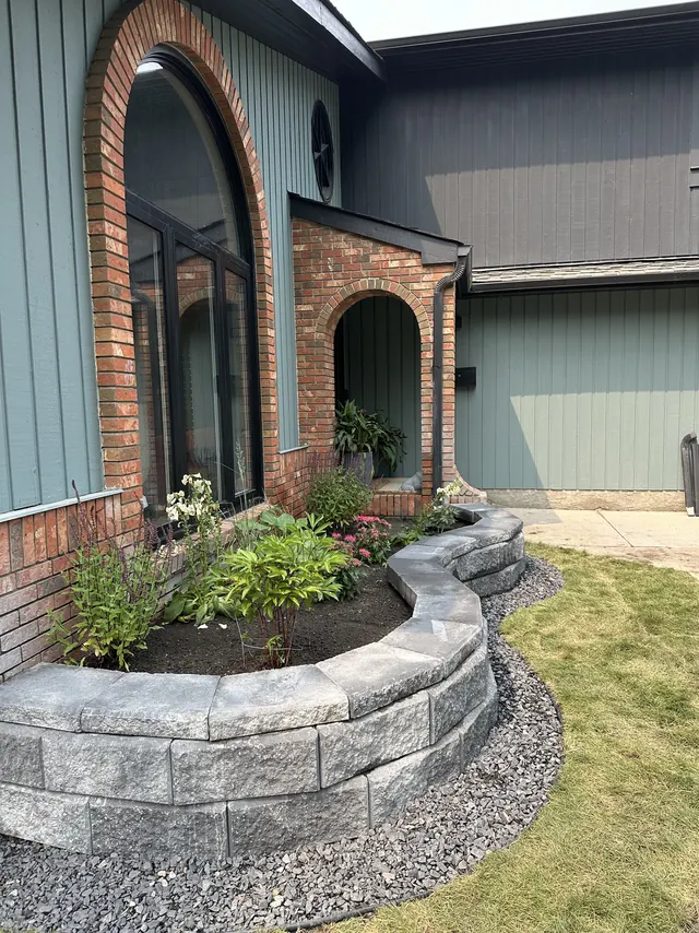 Curved block wall and planting against a brick facade